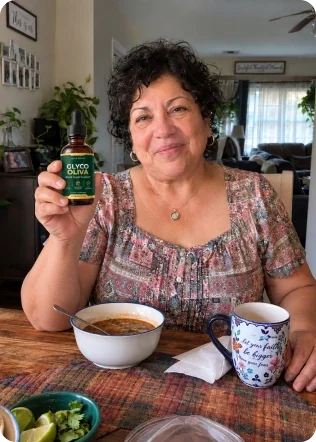 Smiling woman holding a Glyco Oliva bottle at her kitchen table